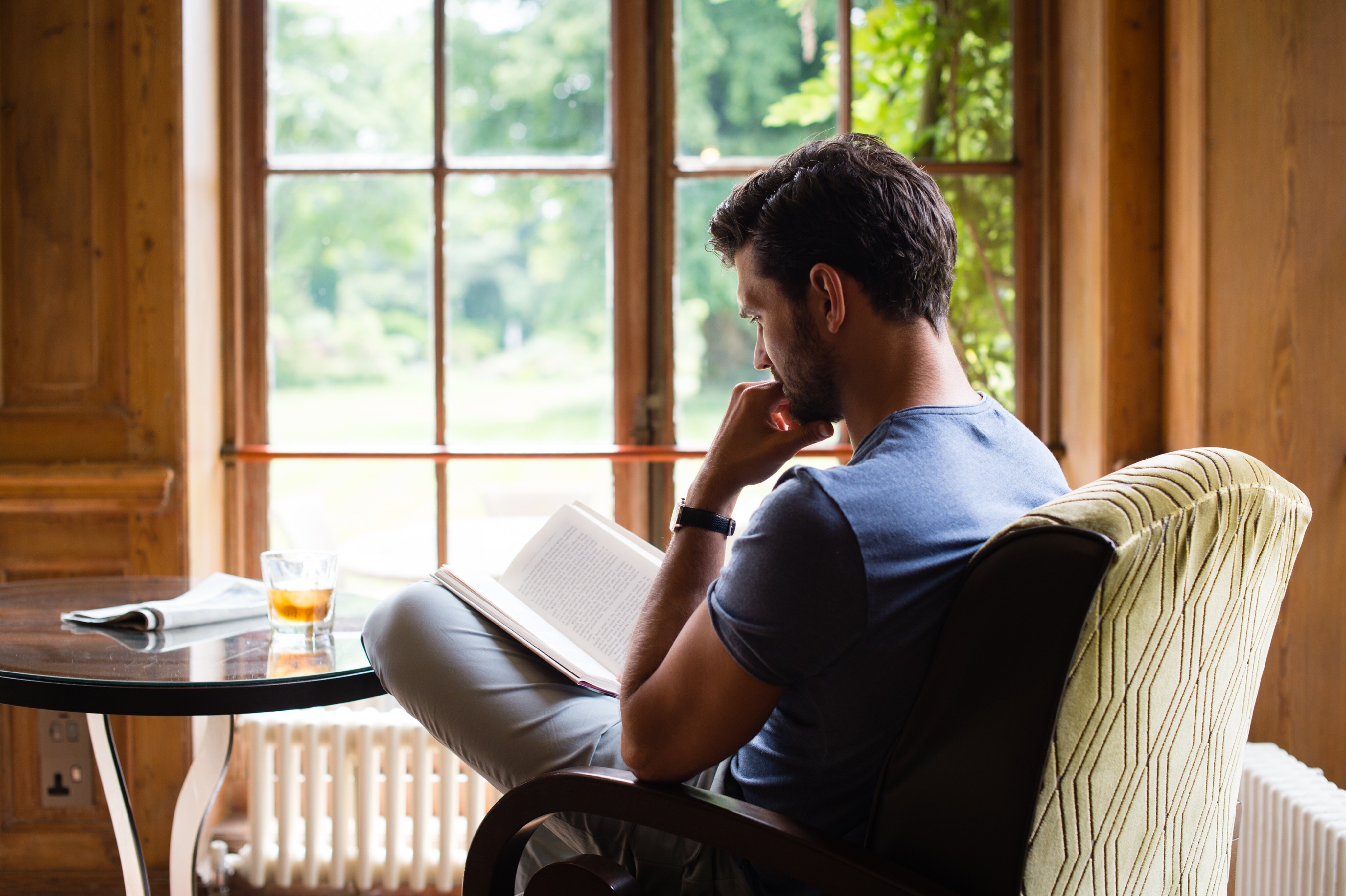 Man in a chair reading a book in a country house hotel